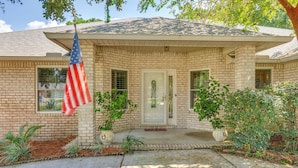 A single-story house with a brick facade, a front porch, and a flagpole with an American flag. - 4 Mi to Beach: Family-friendly Home in Navarre (Navarre)