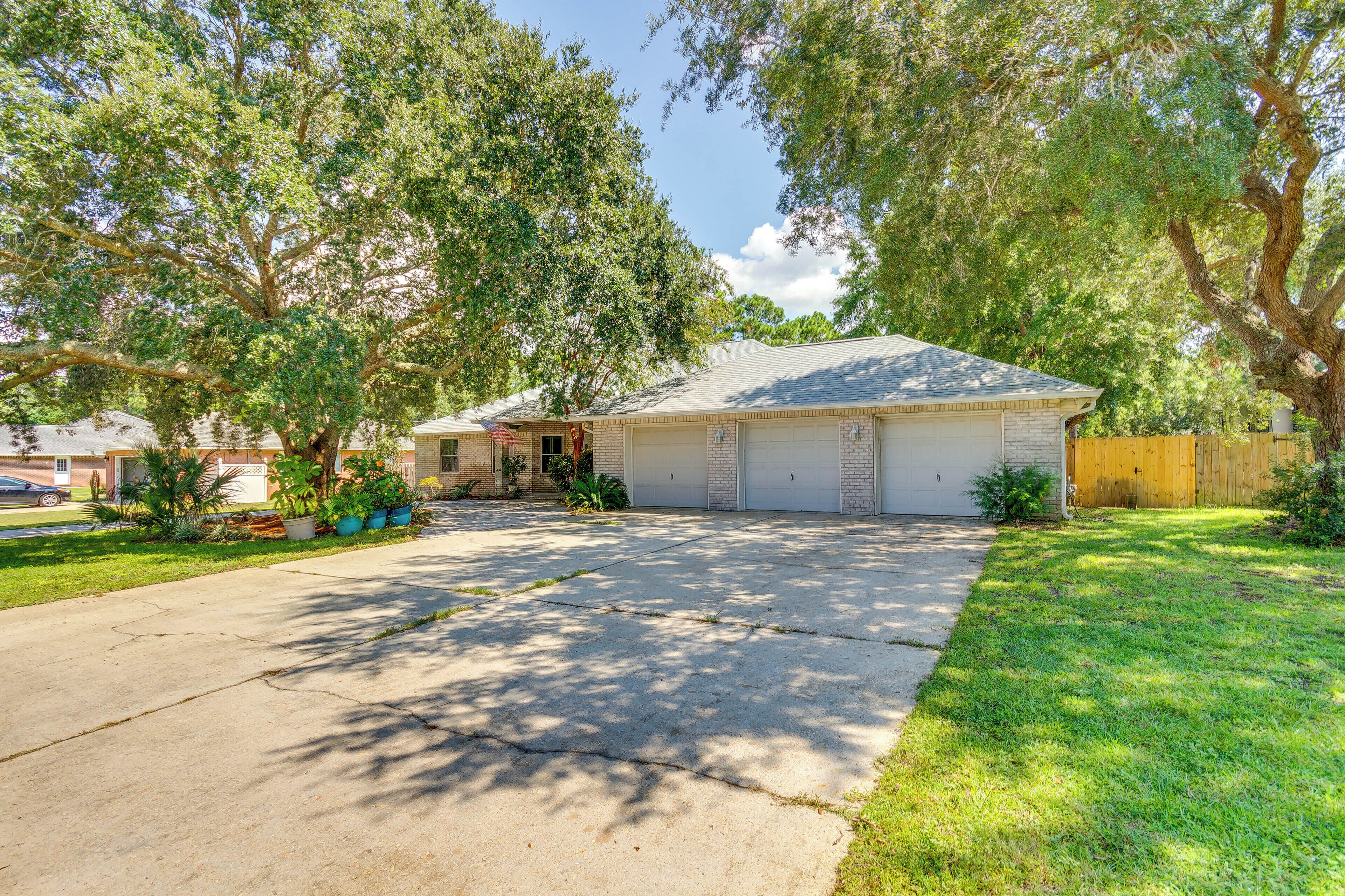 A residential house with a garage, driveway, and surrounding trees.