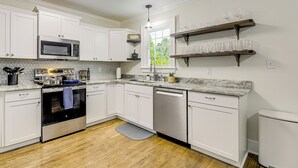 Una cocina moderna con armarios blancos, electrodomésticos de acero inoxidable y suelo de madera.