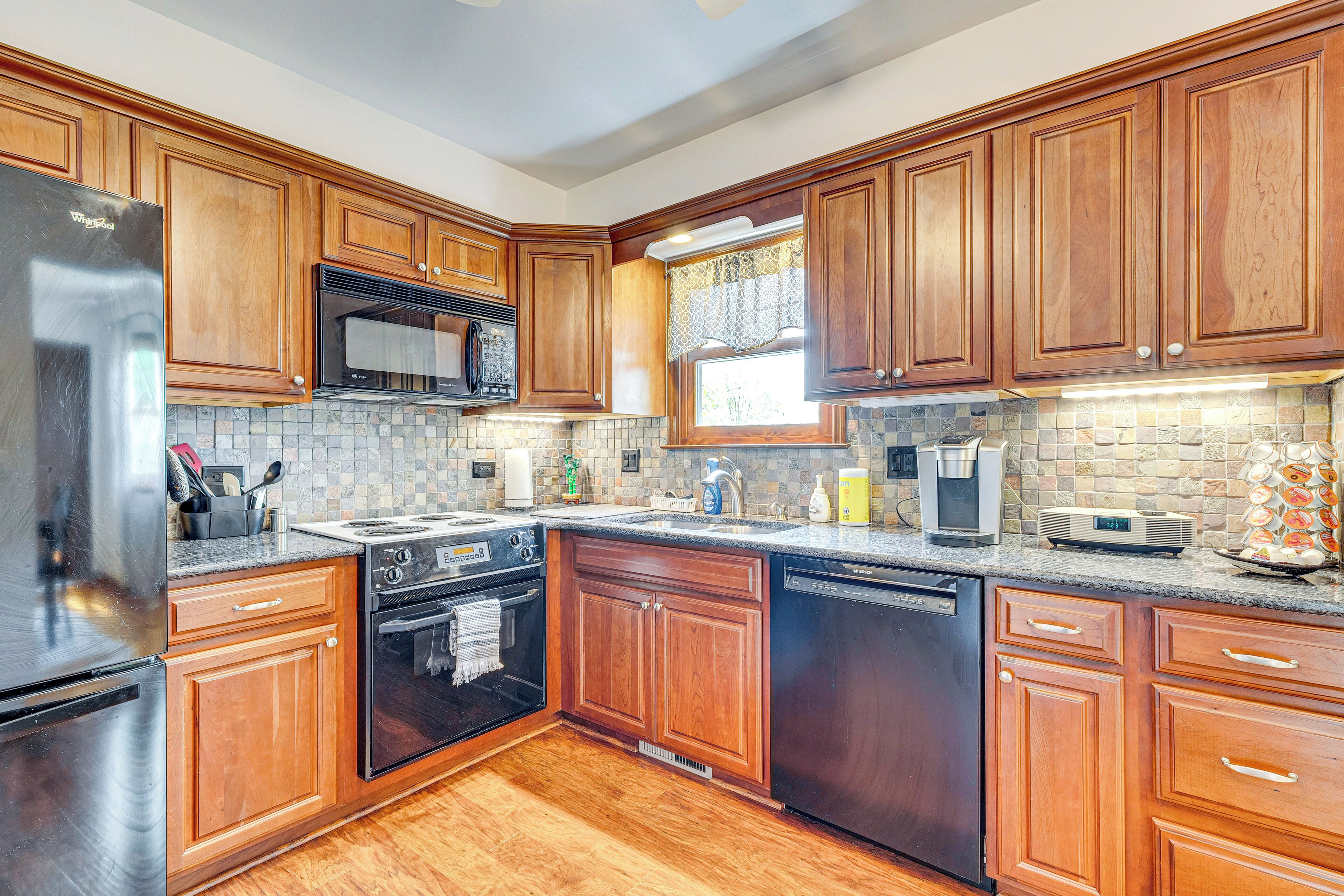 Una cocina con armarios de madera, electrodomésticos de acero inoxidable y salpicadero de azulejos.