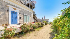 A building with a blue door, a balcony, and a sandy pathway. - Steps to Commercial St! Lofted Provincetown Gem (Provincetown)