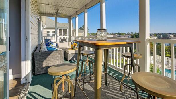 A covered outdoor area with a table, chairs, and a sofa.