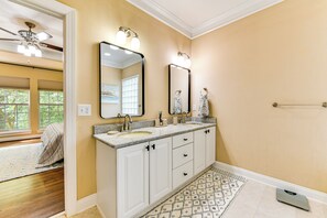 Un baño con dos lavabos, un ventilador de techo y un espejo grande.