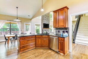 Une cuisine spacieuse avec des meubles en bois, un lave-vaisselle intégré et un mur décoratif en pierre.