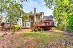 Une maison à deux étages, construite en briques, avec une terrasse en bois et une cheminée.