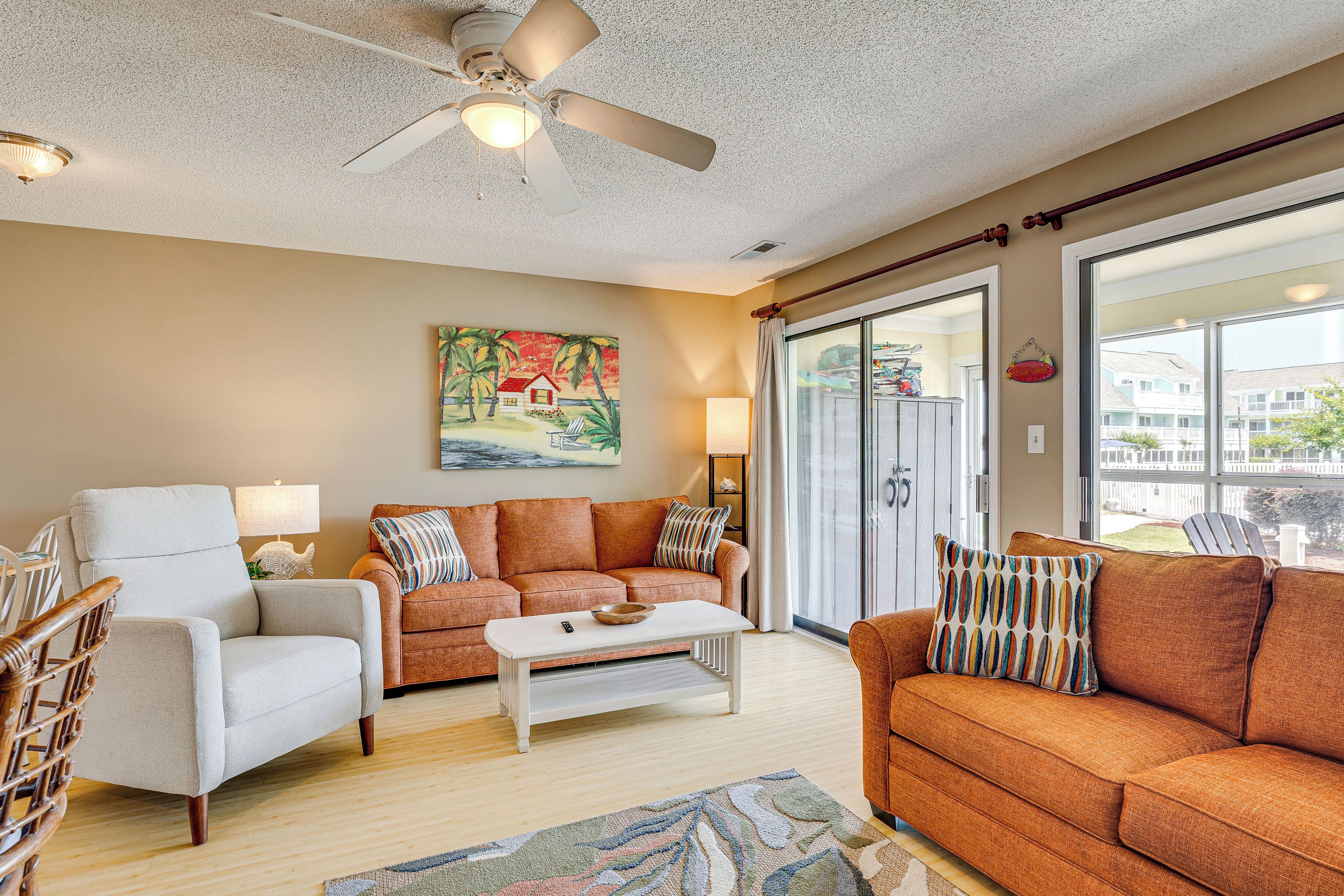 A living room with a white armchair, a brown sofa, a coffee table, and a ceiling fan.