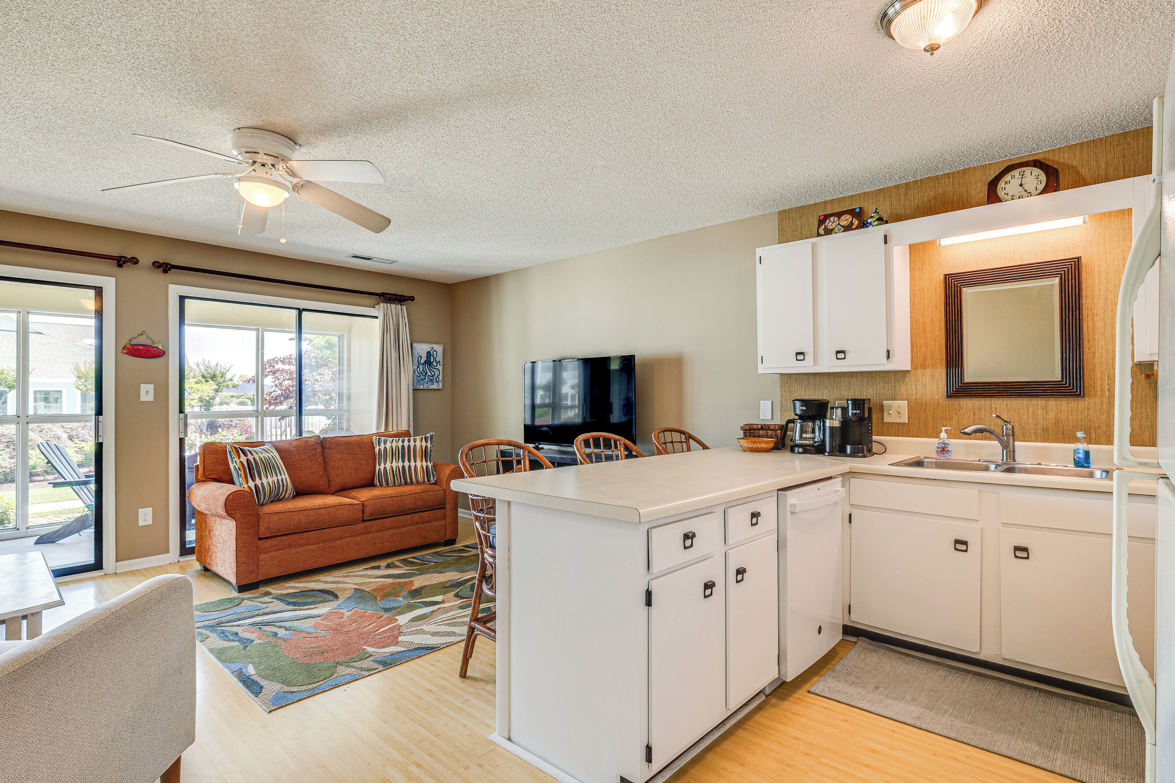A compact kitchen with a dining area, a sofa, and a TV.