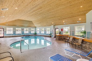 Ein Hallenbad mit Holzboden, Steinwand und einer Sitzecke mit Stühlen.