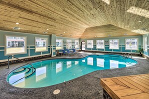 Ein Hallenbad mit Holzbalkendecke, großen Fenstern und einer Lounge mit Sesseln.