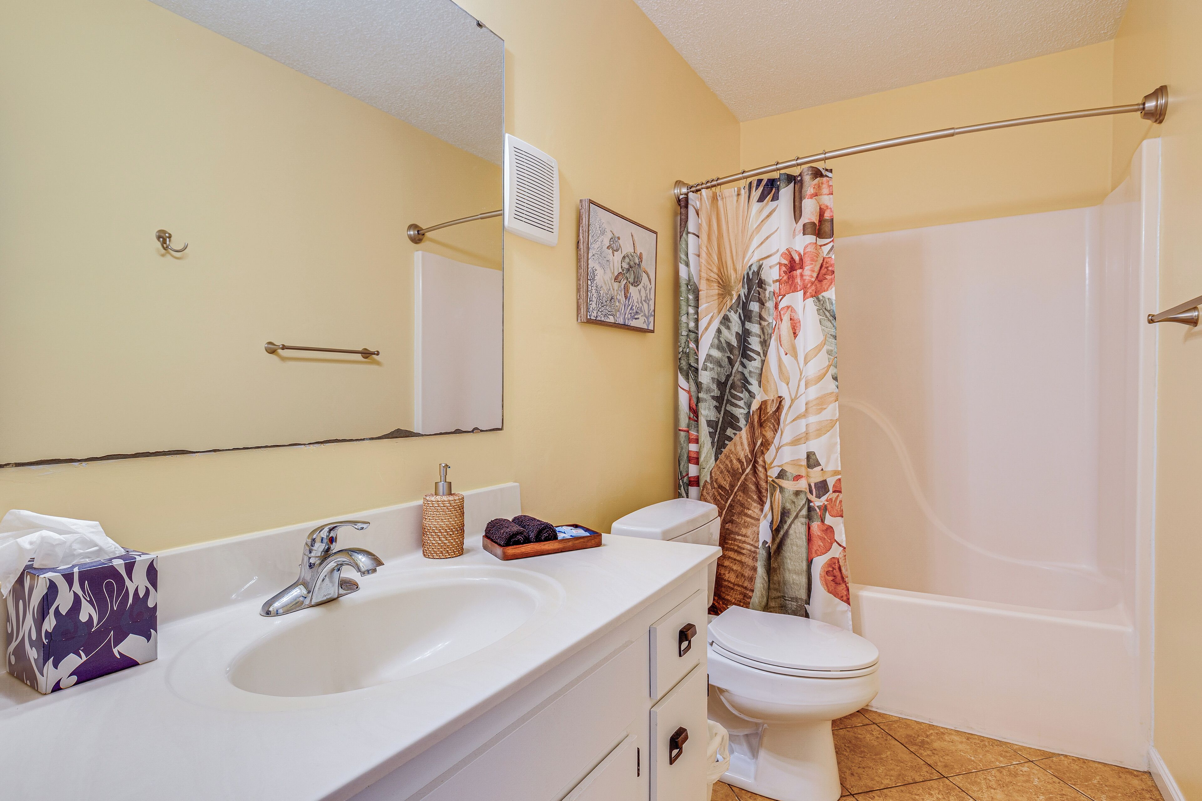 A bathroom with a sink, mirror, toilet, and shower curtain.