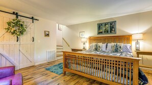Une chambre à coucher avec un lit en bois, un fauteuil en cuir rouge, une armoire en bois et une porte en bois.