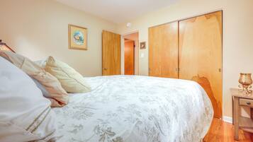 A bedroom with a bed, a wooden wardrobe, and a nightstand with a lamp.