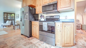 Una cocina con armarios de madera, electrodomésticos de acero inoxidable y una zona de comedor con sillas y una mesa.