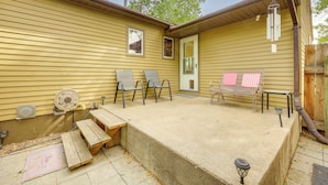 Una casa amarilla con un patio, mobiliario exterior y una terraza de madera.