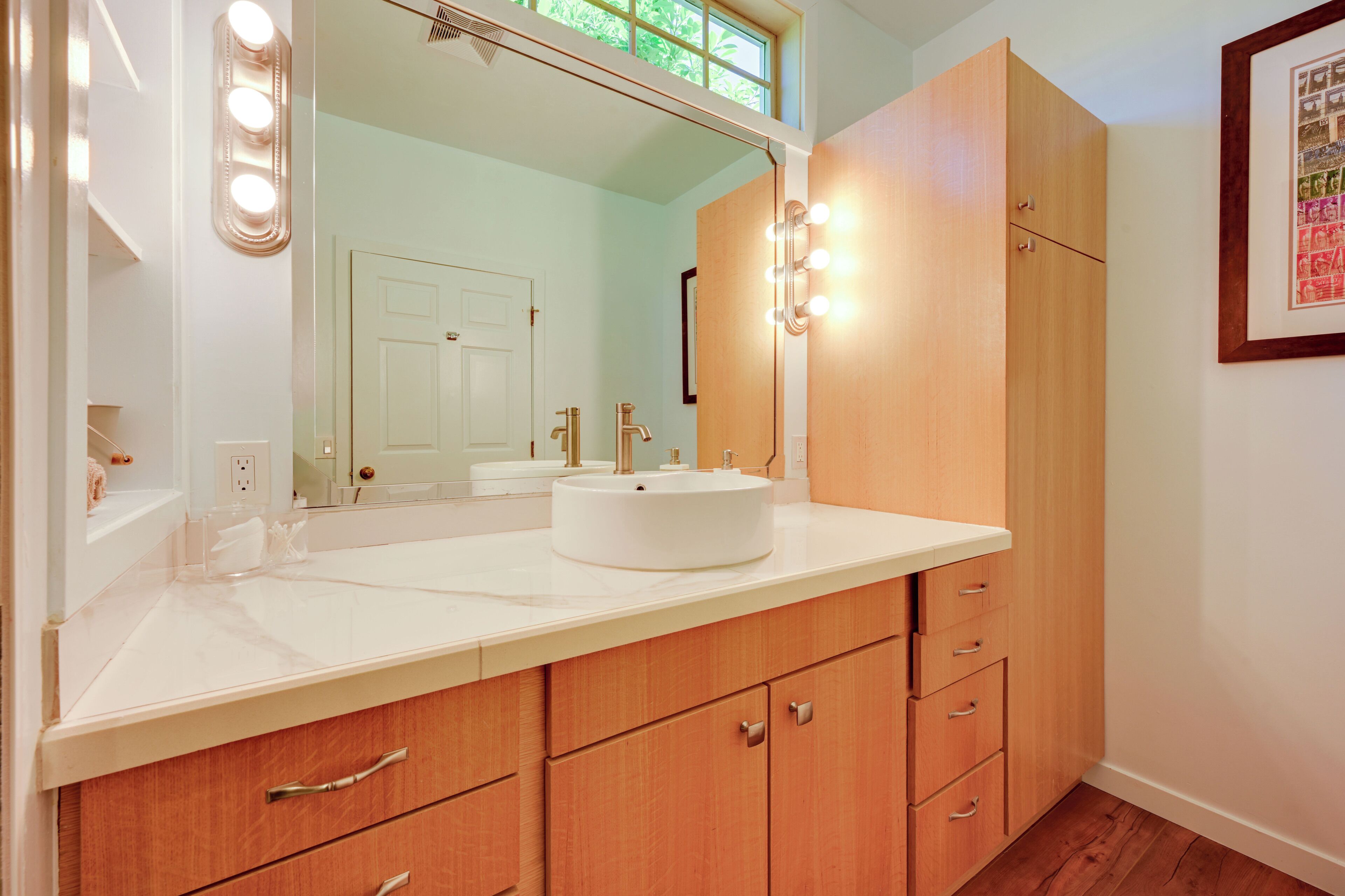 A bathroom with a vanity, mirror, and lighting.