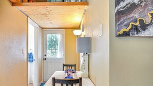 Un'area pranzo con un tavolo apparecchiato per due, una lampada e un quadro appeso al muro.