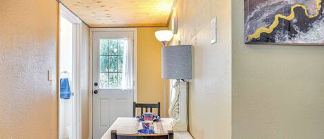 A dining area with a table set for two, a lamp, and a painting on the wall.