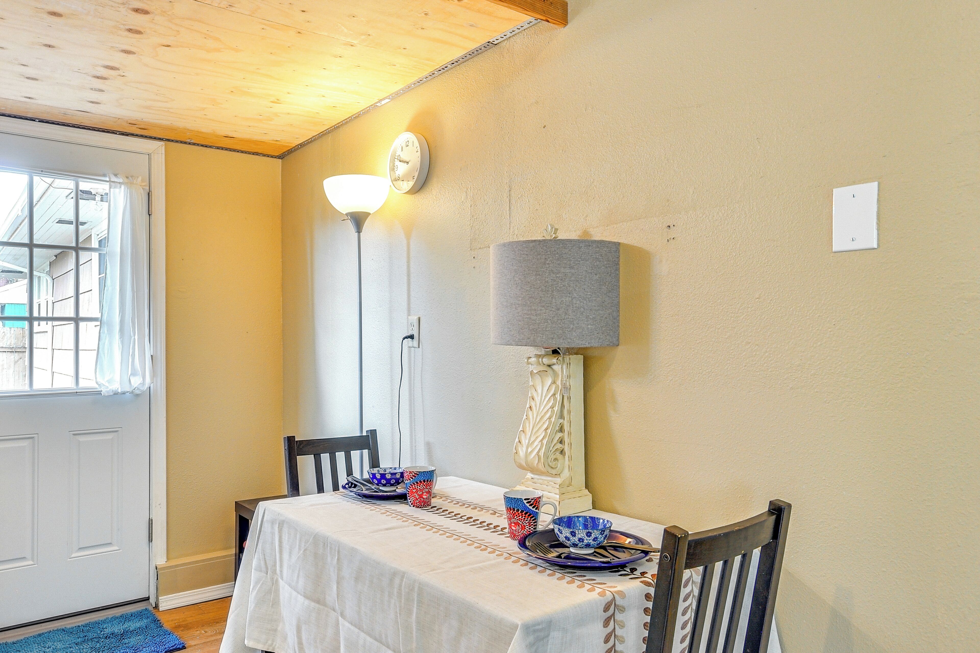 Een eethoek met een tafel gedekt voor twee personen, een lamp en een klok aan de muur.