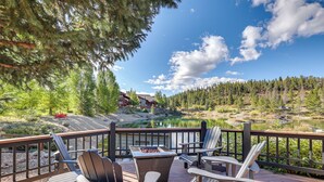 Una terraza con sillas tipo Adirondack, un brasero y vistas a un lago y bosque.