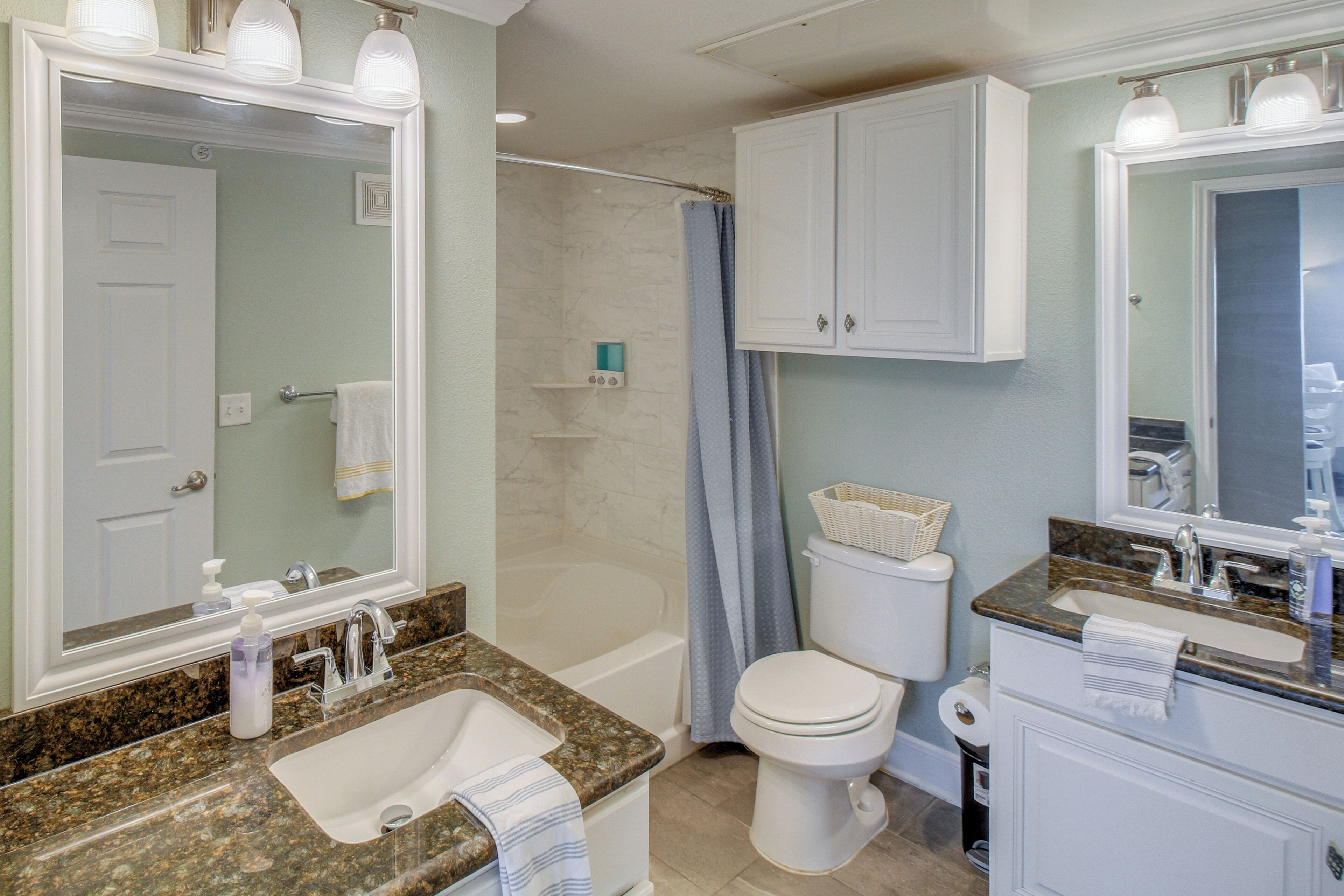 A bathroom with a sink, toilet, bathtub, and mirrors.