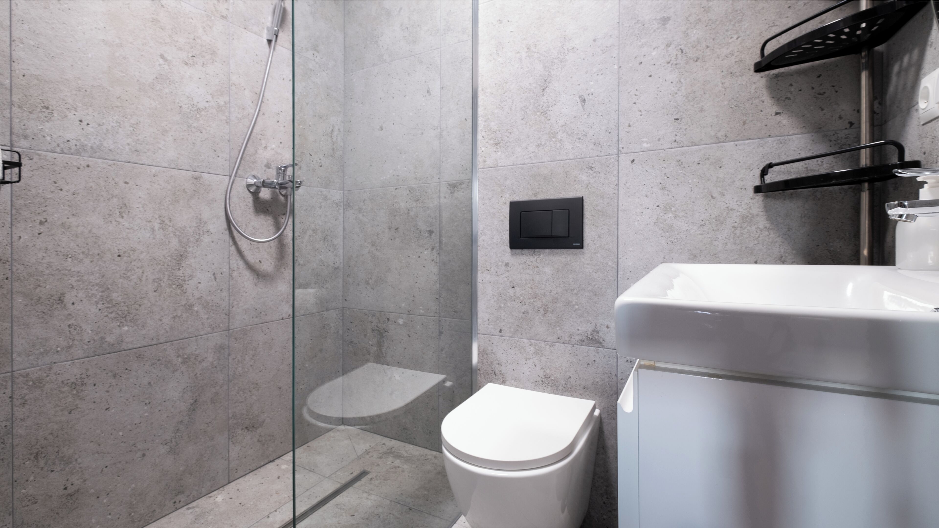 A modern bathroom with a glass shower enclosure, a white toilet, and a white sink.