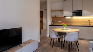 A modern kitchen with a dining area, a flat-screen TV, and a coffee maker on the counter. - Apartamenty Sun & Snow River Park (Wisla)