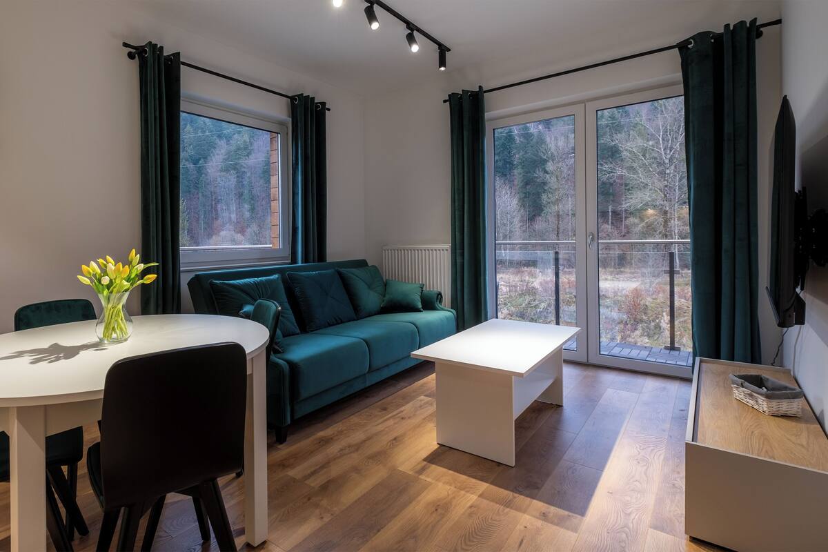 A modern living room with a dining table, chairs, a sofa, and a TV.