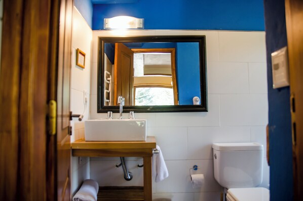 Une salle de bain avec un lavabo blanc, un miroir, des toilettes et un mur bleu.