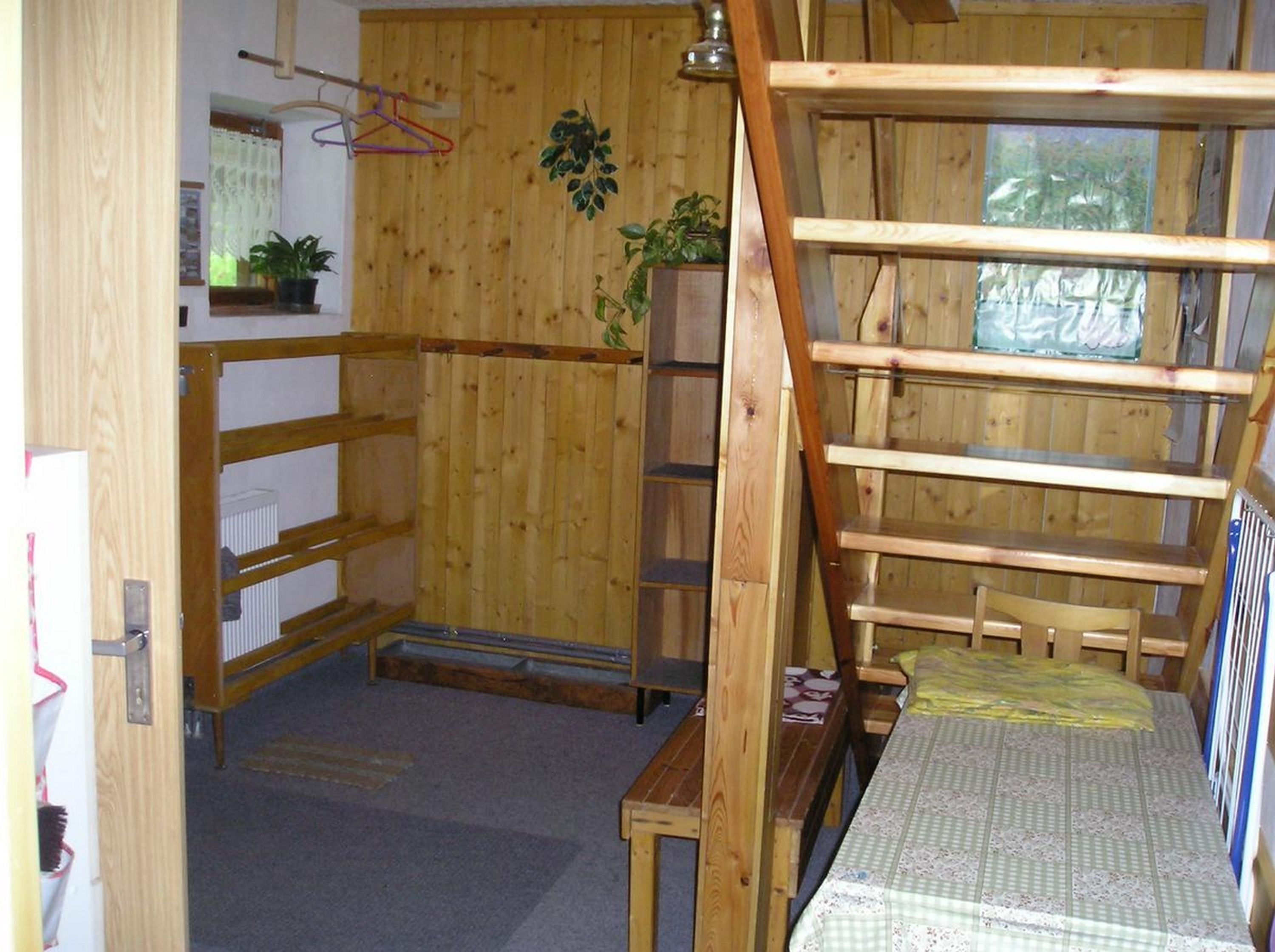 A compact wooden room with a bunk bed, a small table, and a radiator.