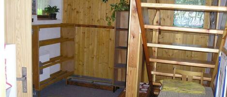 A compact wooden room with a bunk bed, a small table, and a radiator.