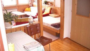 A compact room with a bed, a small table, and a chair.