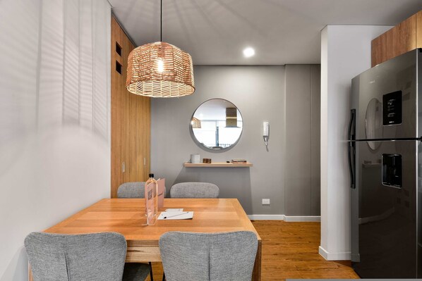 A modern kitchen with a built-in refrigerator, wooden cabinets, and a round mirror above the countertop.