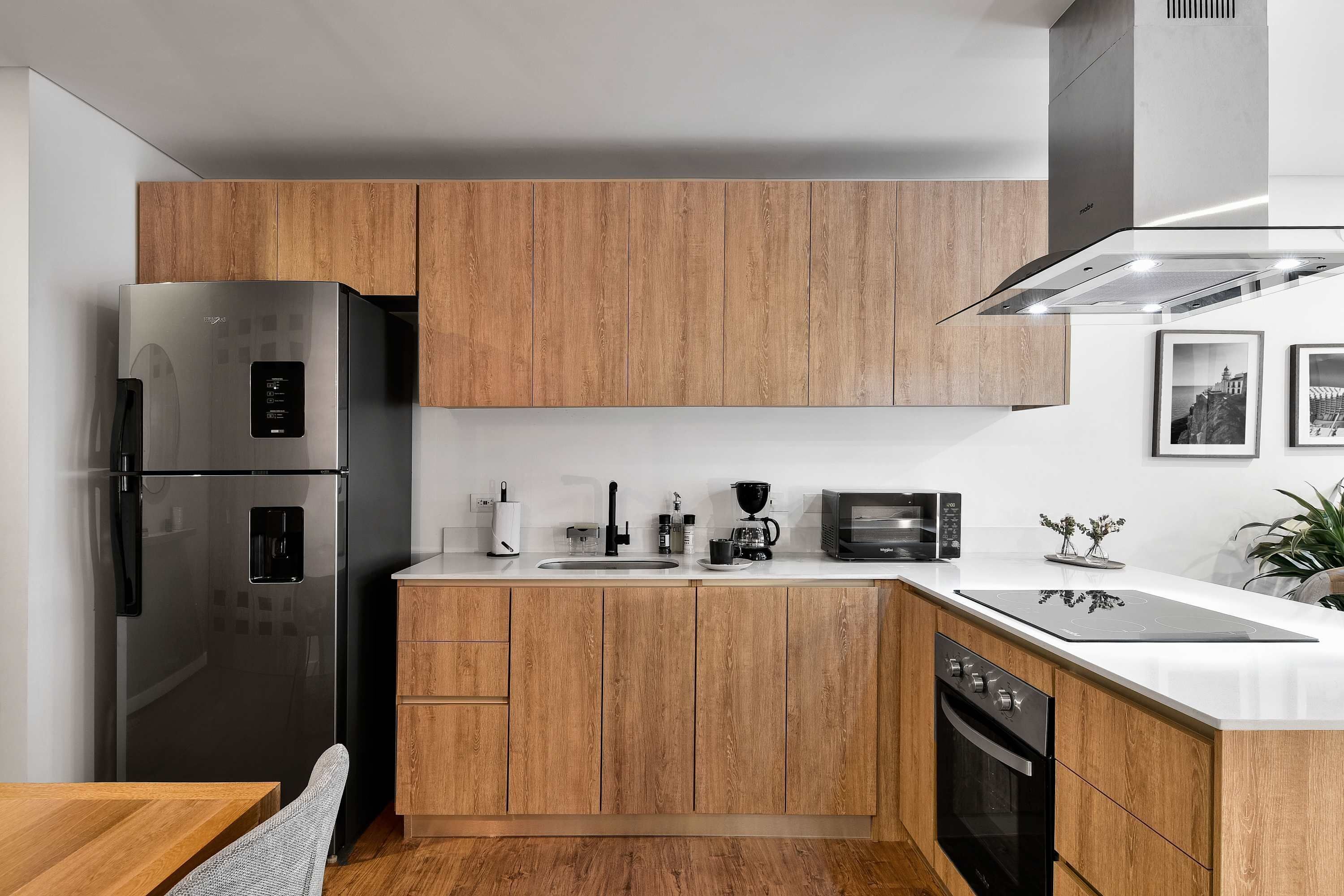 A modern kitchen with wooden cabinets, stainless steel appliances, and a white countertop.