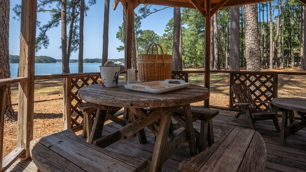 A wooden deck with a table and chairs, overlooking a lake with trees. - Minutes from Downtown St. Michaels | Private Boat Ramp | Dock (Bozman)