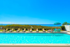 A swimming pool with lounge chairs and a view of the ocean.