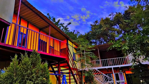 A multi-story building with a vibrant exterior, featuring a balcony and a staircase. - KUMBH GANGA RETREAT (Karchana)