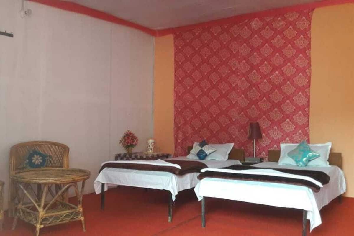 Quarto com duas camas, uma mesinha e duas cadeiras de vime.