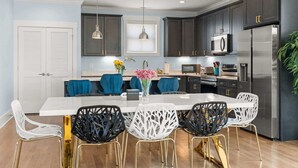 A modern kitchen with dark cabinets, stainless steel appliances, and a central island with chairs. - Chic Townhome for 8 w/Rooftop (Nashville)