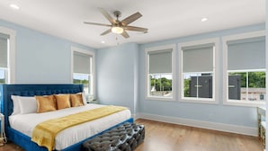 A bedroom with a large bed, a ceiling fan, and multiple windows. - Chic Townhome for 8 w/Rooftop (Nashville)