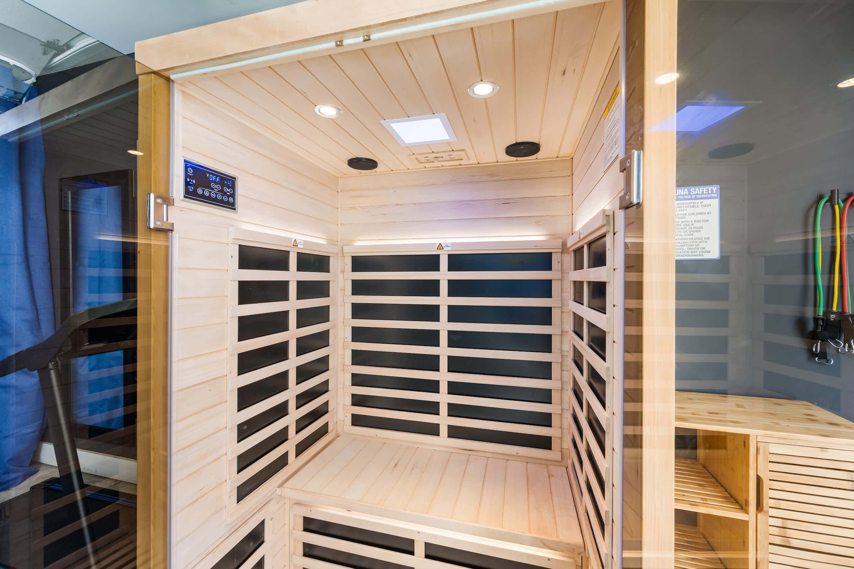 Una sauna con paredes de madera y bancos de listones, un panel de control y un letrero de seguridad.