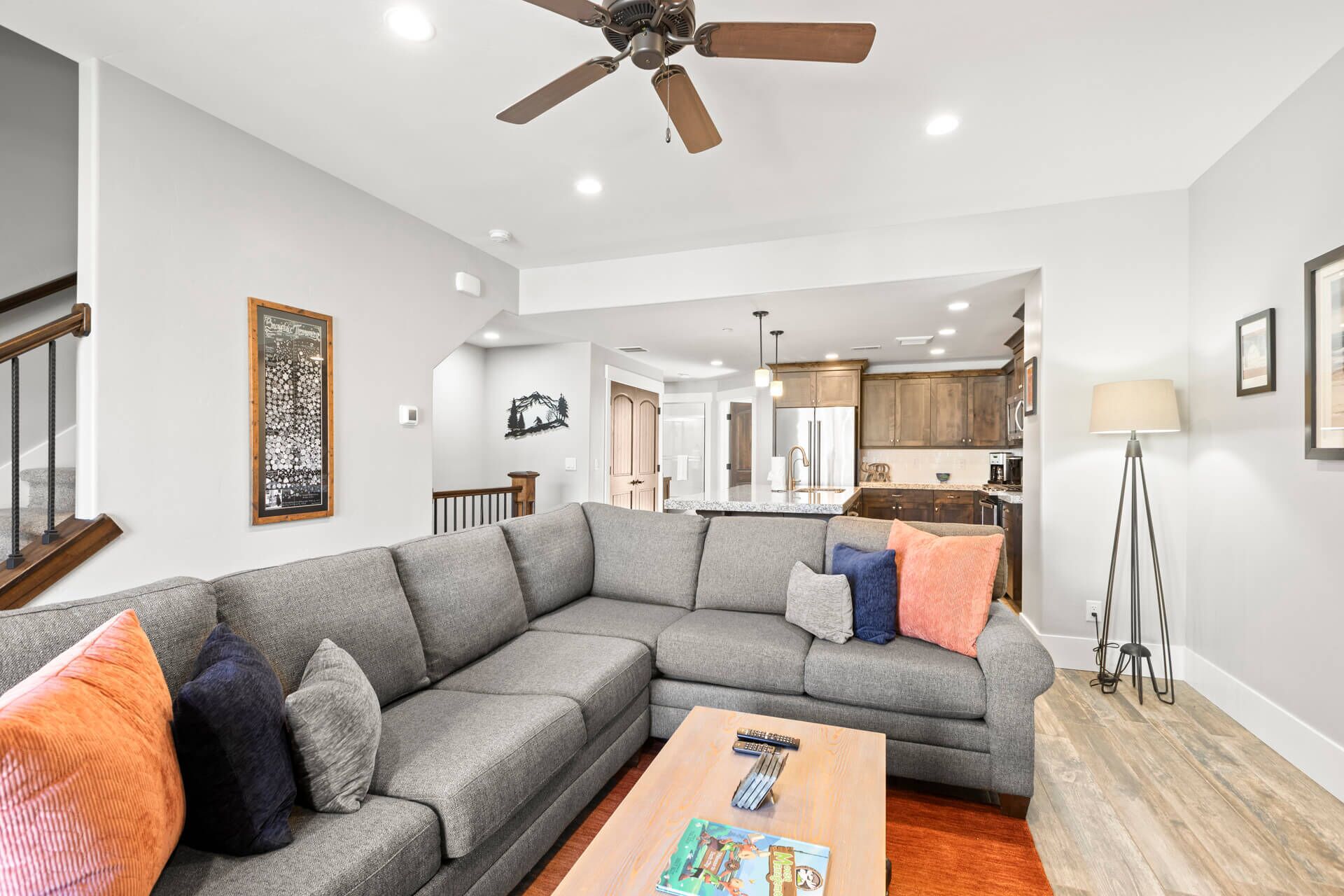 A modern living room with a gray sectional sofa, a wooden coffee table, and a ceiling fan.