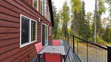 Guests can enjoy a deck with a table and chairs, overlooking a scenic path surrounded by trees.