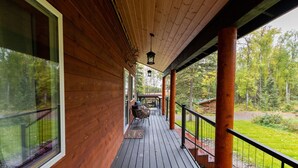 Une terrasse en bois avec une rambarde, un banc et une lanterne suspendue.