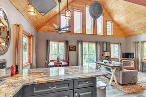 Una cocina amplia con encimera de mármol, techo de madera y ventanas grandes.