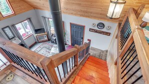 Un escalier en bois avec une rampe, un plafond en bois et un luminaire suspendu.