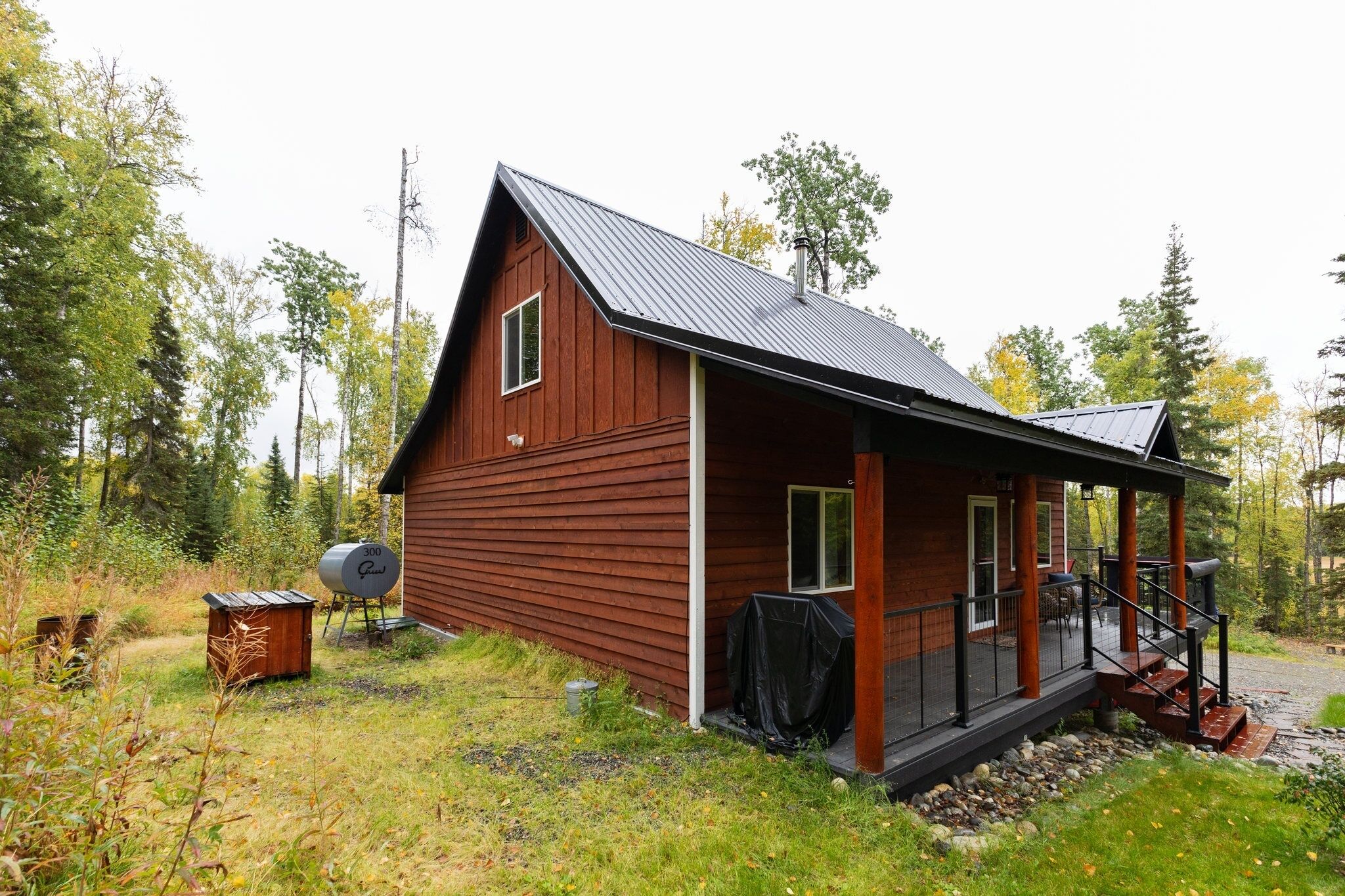 A wooden cabin with a porch, a satellite dish, and a covered outdoor seating area.