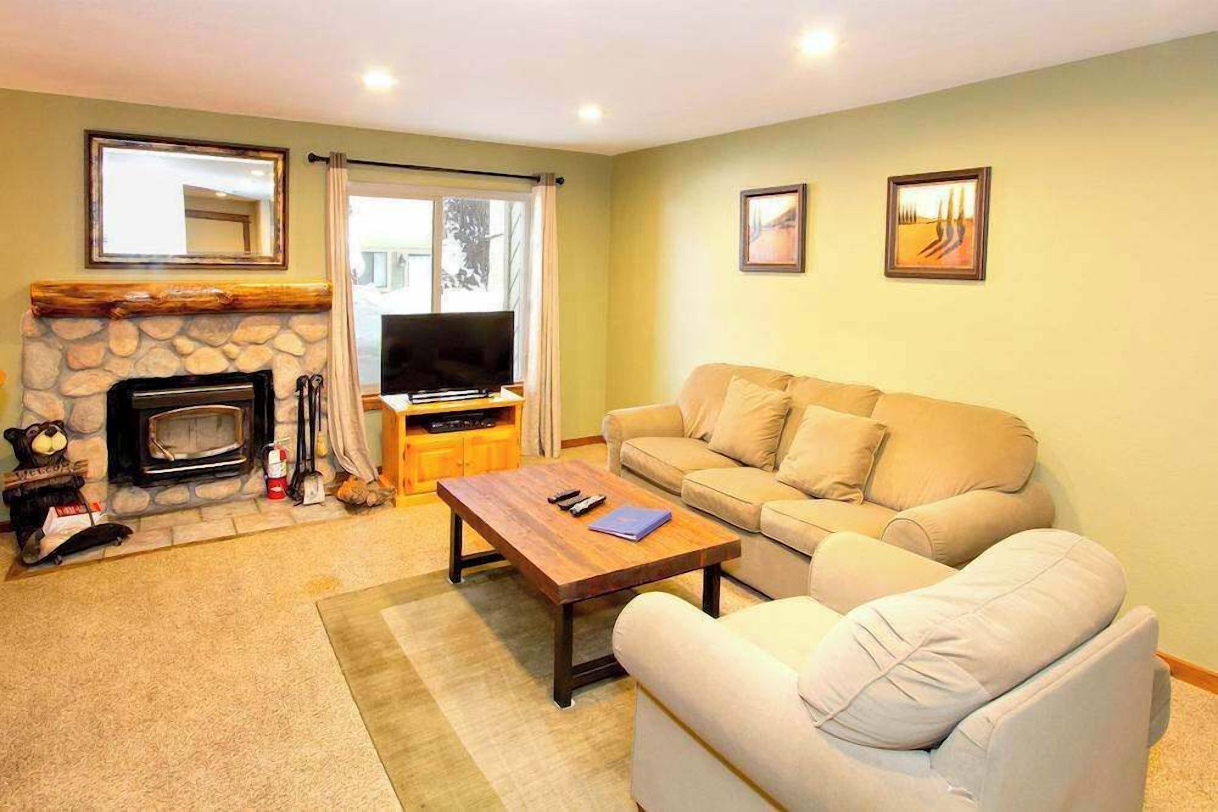 A living room with a stone fireplace, a television, a sofa, and a coffee table.