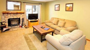 Una sala de estar con chimenea de piedra, televisor, sofá y mesa de centro.