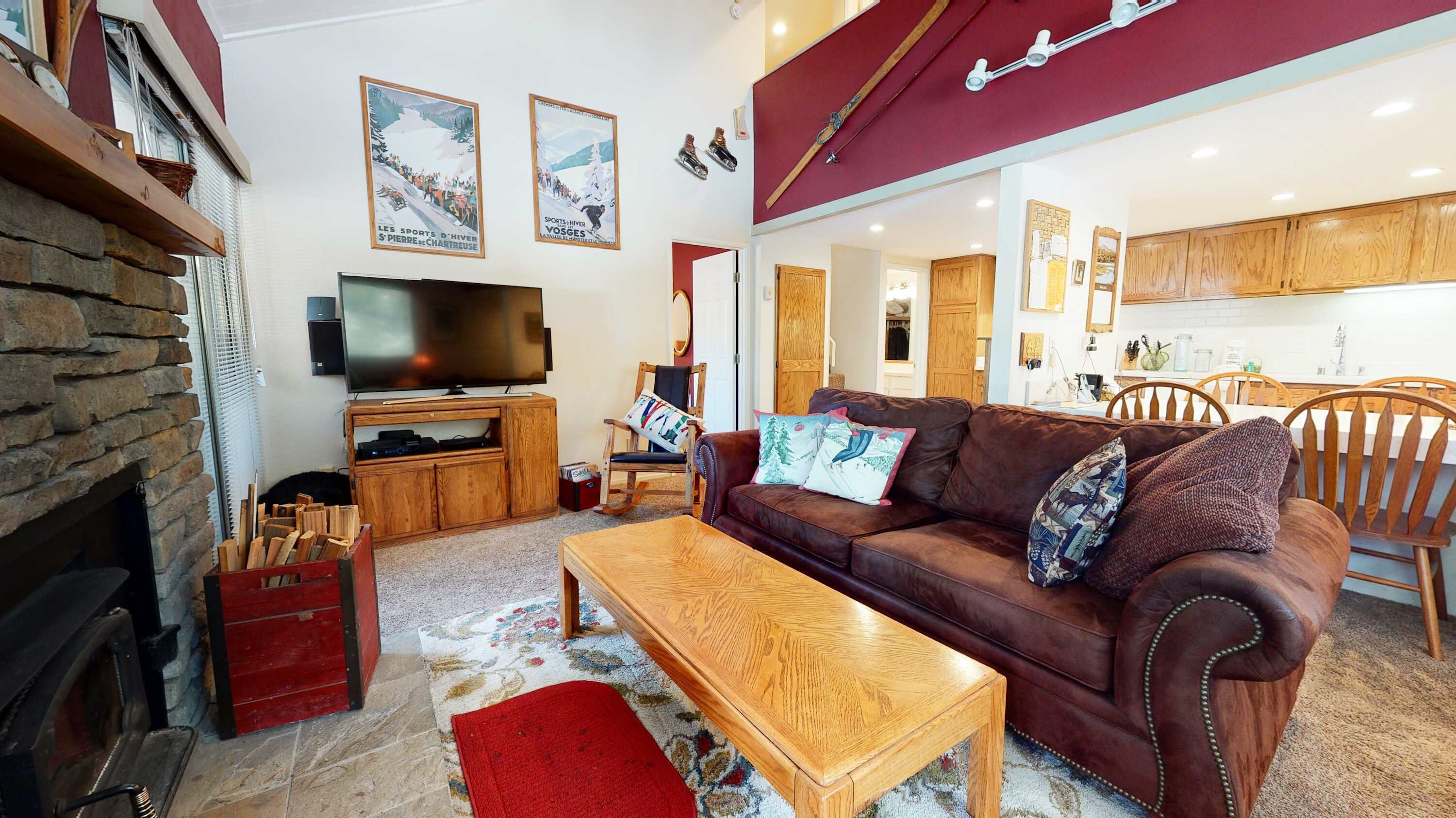 A cozy living room with a fireplace, a television, a brown leather sofa, and a wooden coffee table.