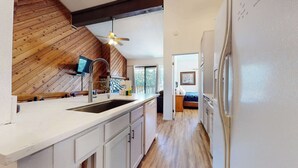 A modern kitchen with a wooden ceiling, a built-in sink, and a ceiling fan.